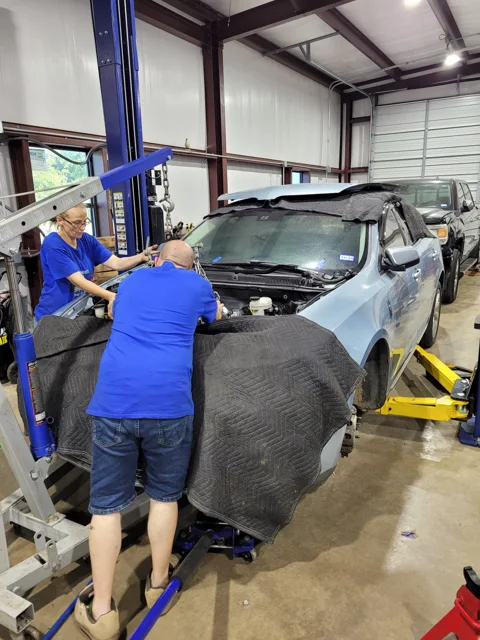 Hands-on engine work over a protected fender
